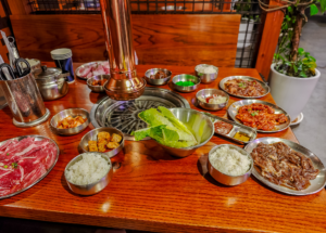 korean barbecue restaurant table with grill and side dishes